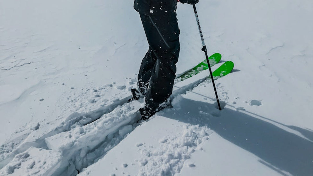 Skier with green skis and poles in deep snow