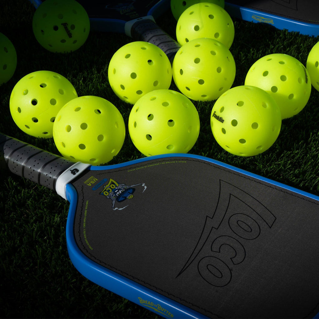 Bread & Butter Loco Elongated Pickleball Paddle - Blue/Gray, on turf with balls