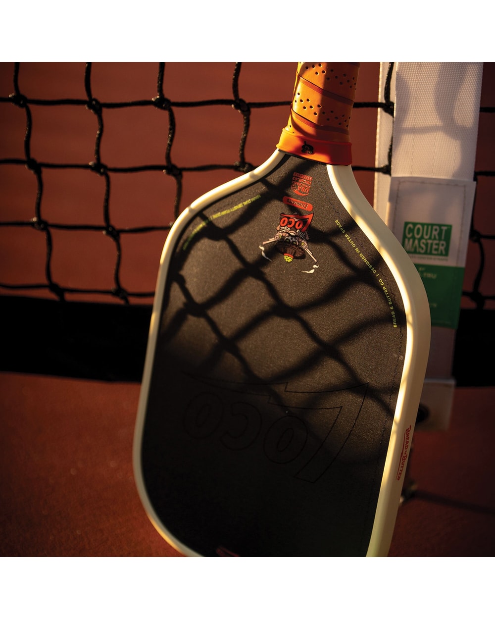 Bread & Butter Loco Elongated Pickleball Paddle - Cream/Tan, angled view at net