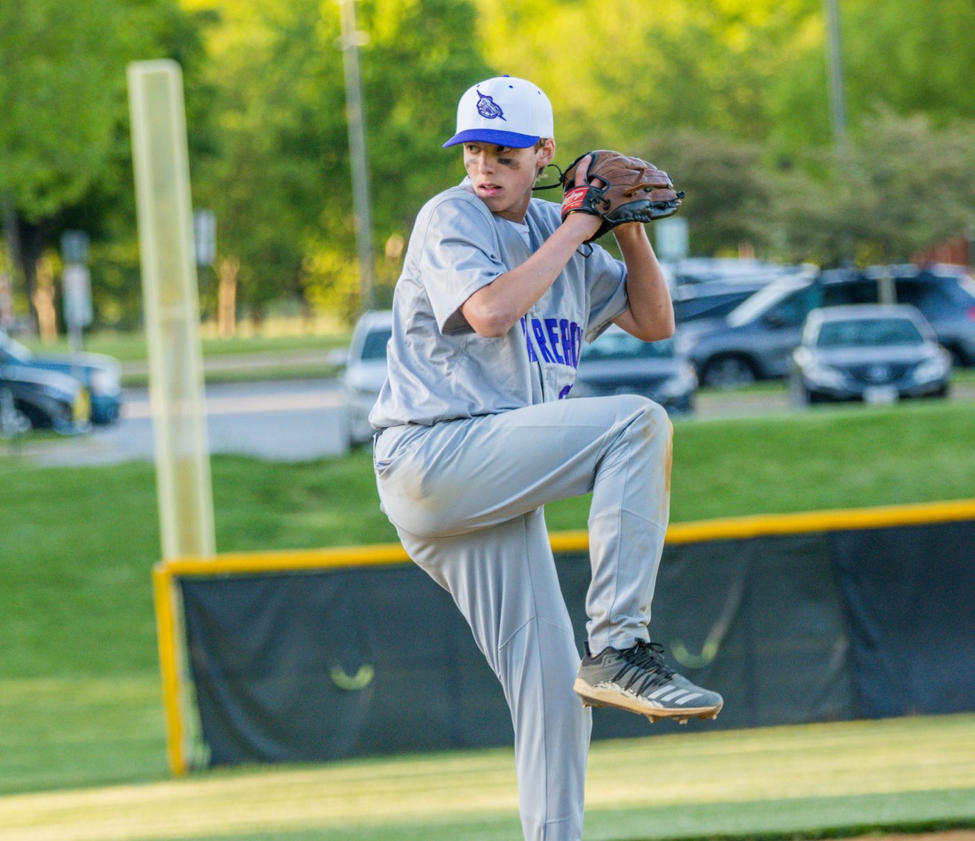 Baseball pitcher in royal blue cap winding up to deliver a pitch