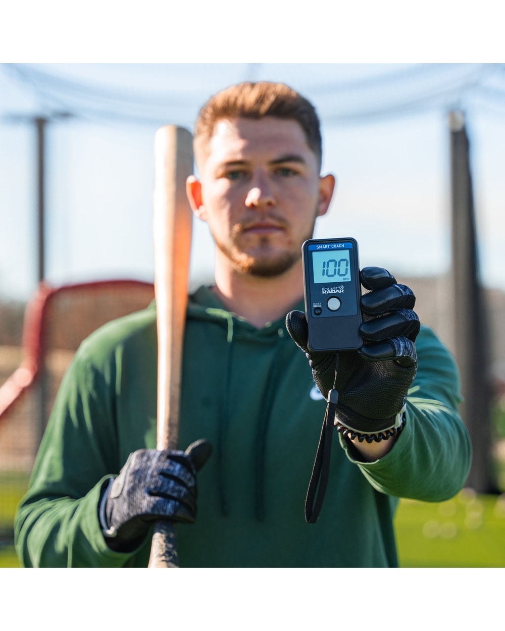 Baseball player holding the Pocket Radar Smart Coach showing a 100 mph reading
